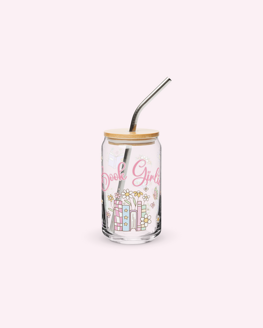 A clear bookish glassware with pink book girlie text and floral designs, a wooden lid, and a silver metallic straw.